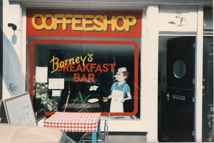 The original Barney’s Breakfast Bar shop window with red and yellow lettering, the Barney character and a red-and-white checked tablecloth.